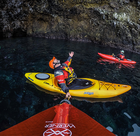 happy paddlers in Jackson Kayak Traverse boats in a cave holding a red Werner Paddle