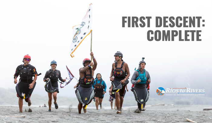 several youth heading toward the sea with the paddle tribal waters flag