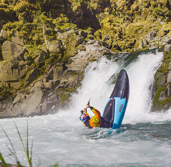 dane jackson at the base of a waterfall in the clutch jackson kayak