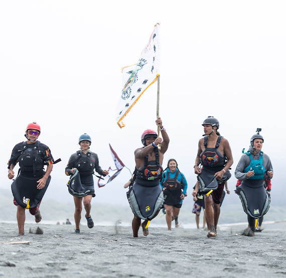 triumphant paddlers running toward the sea with their tribal flag