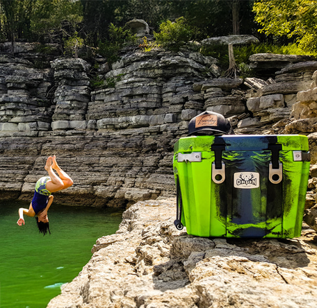orion cooler sitting on limestone cliffs with adventurous person jumping into the lake below