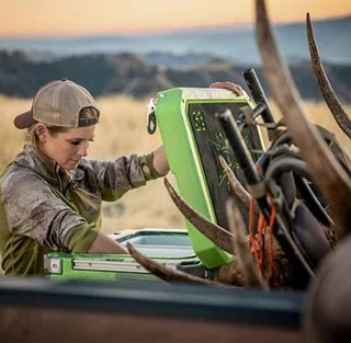 An Orion Cooler in the back of the truck with an elk shed in the background.