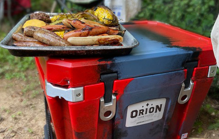 Food on a tray that's on top of an Orion Cooler.