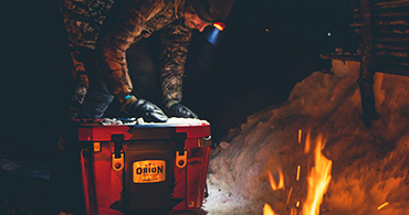 Person looking around an Orion Cooler next to a fire for mobile.
