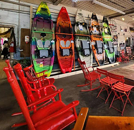 welcoming scene with adirondack chairs and recreational kayaks lined up on the wall