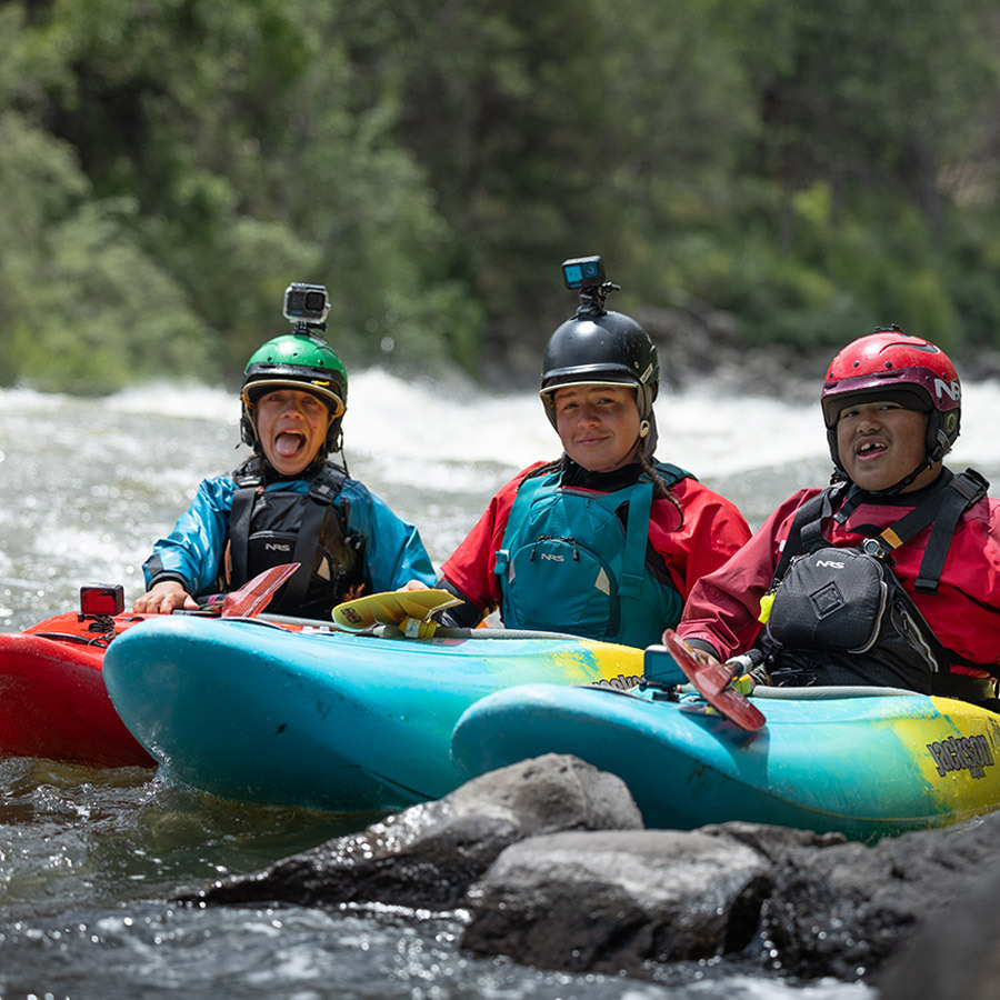 paddlers staging boats on shore in advance of an expedition - rios to rivers logo
