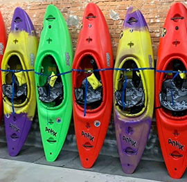 A row of Antix kayaks lined up against a brick wall.